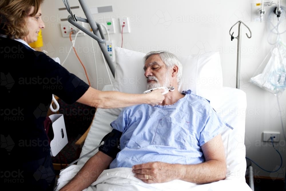 Middle aged male patient being treated by a nurse in a hospital ward - Australian Stock Image