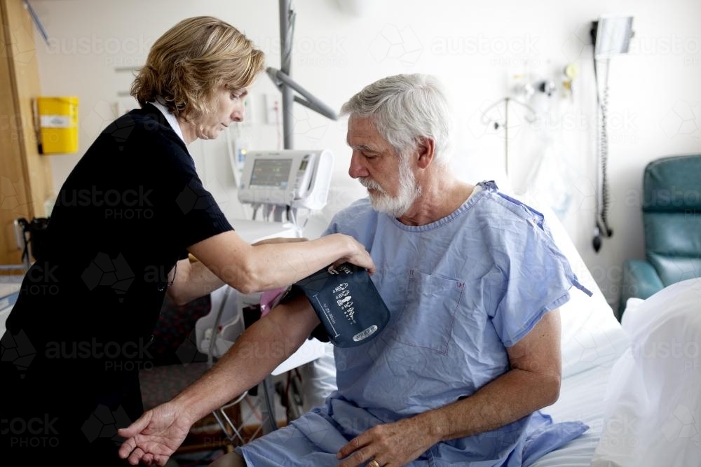 Middle aged male patient being treated by a nurse in a hospital ward - Australian Stock Image