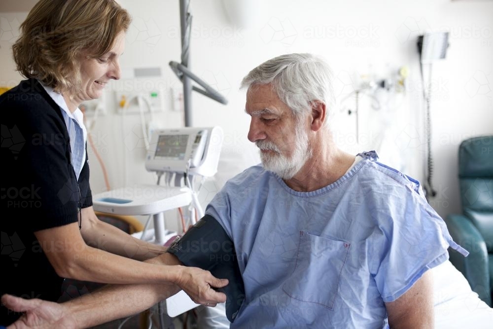 Middle aged male patient being treated by a nurse in a hospital ward - Australian Stock Image