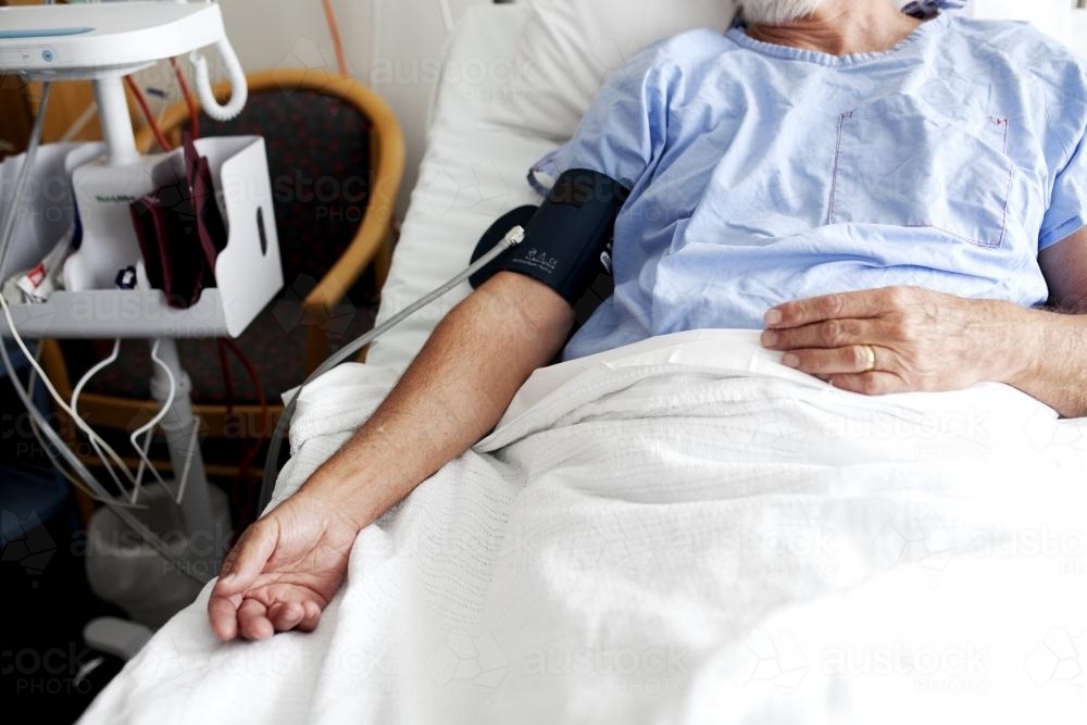 Middle aged male patient lying in a hospital ward - Australian Stock Image