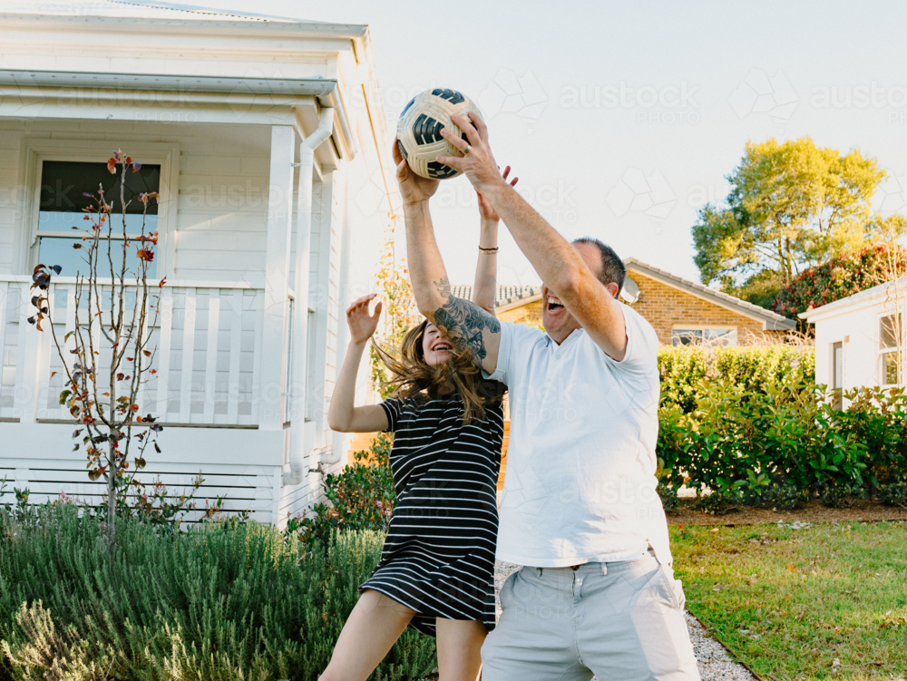 Middle aged man and teenage girl catching the soccer ball. - Australian Stock Image