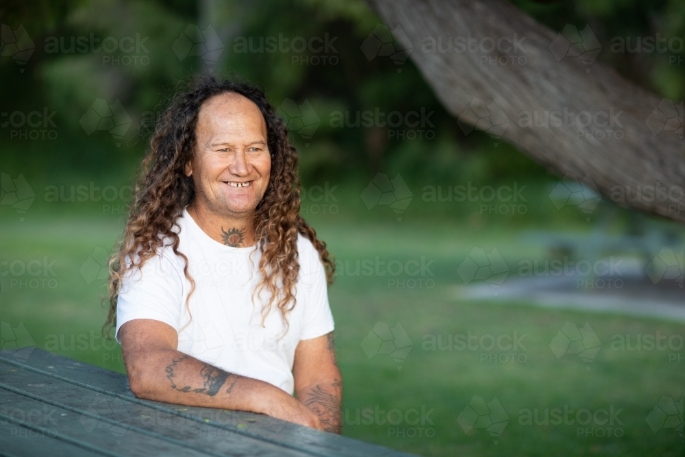 middle-aged man sitting outdoors in park - Australian Stock Image