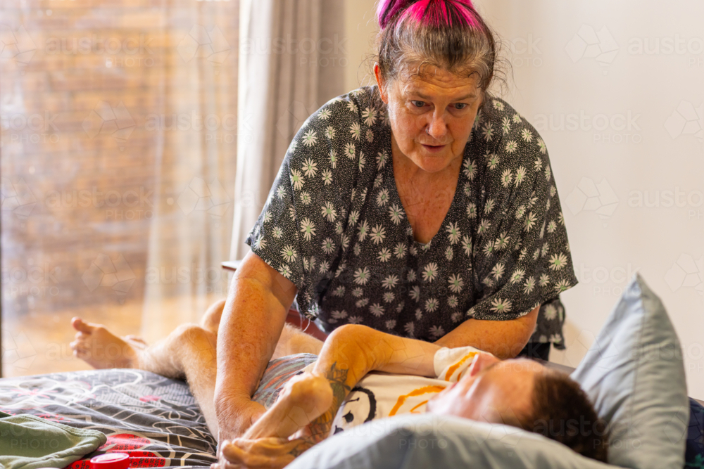 Image of Middle-aged mum helping young son with disability be in ...