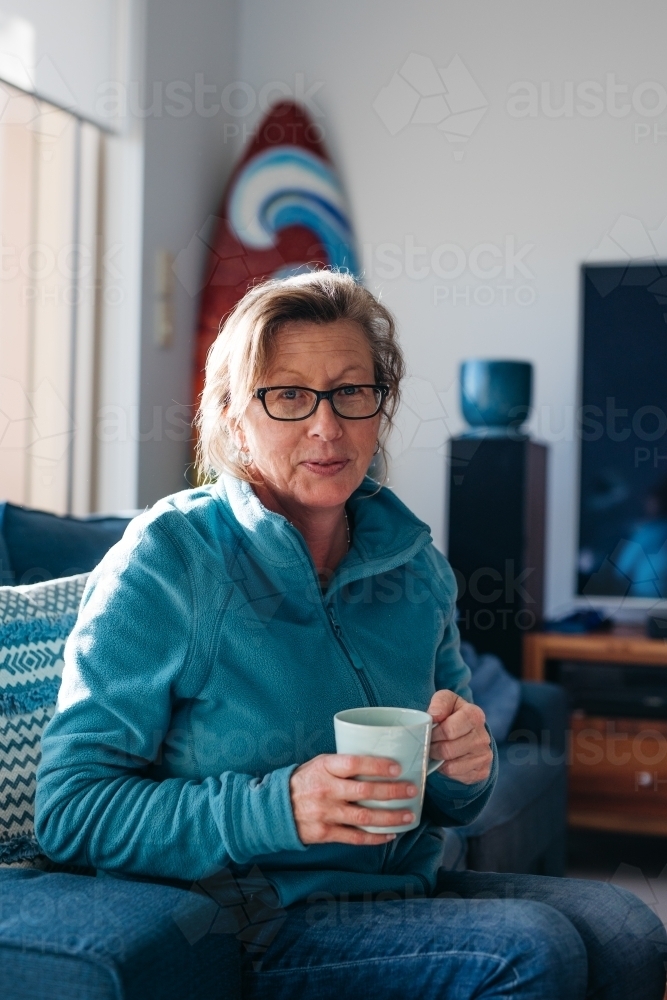 Middle aged woman looking happy with mug in hand - Australian Stock Image