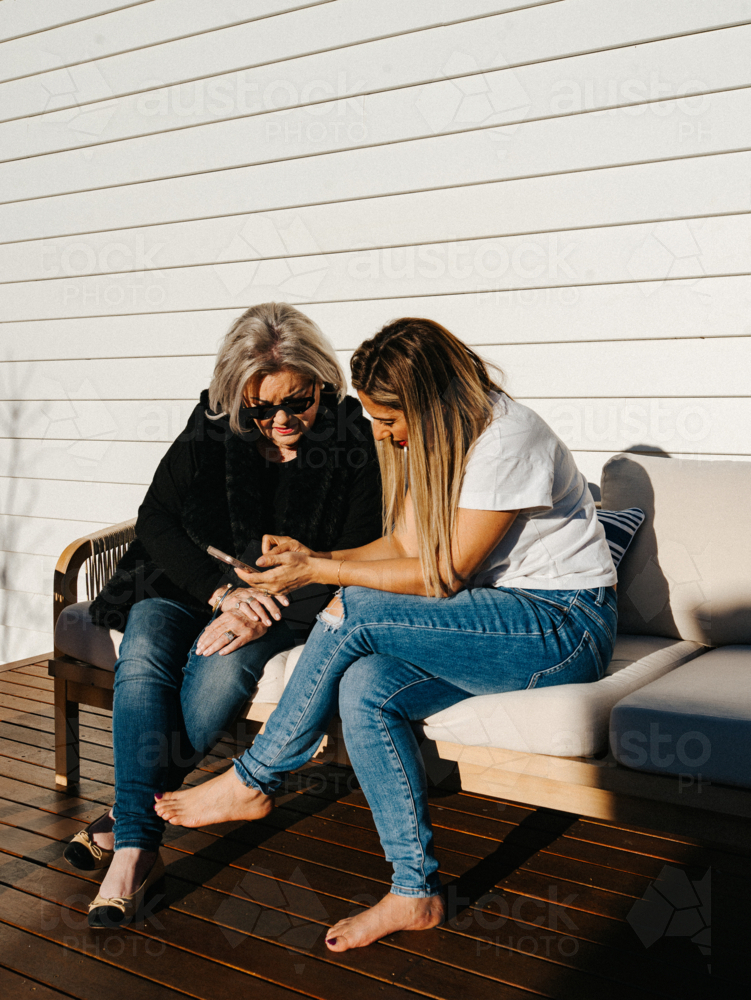Middle aged woman showing an elderly person a mobile device - Australian Stock Image