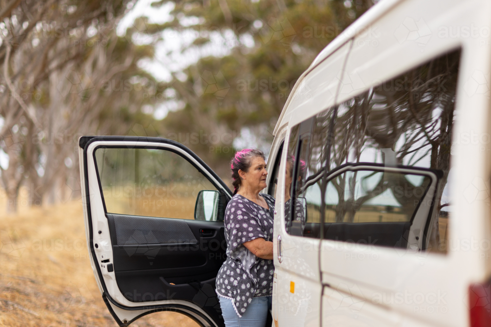 Middle aged woman standing beside the opened passenger seat of white van - Australian Stock Image