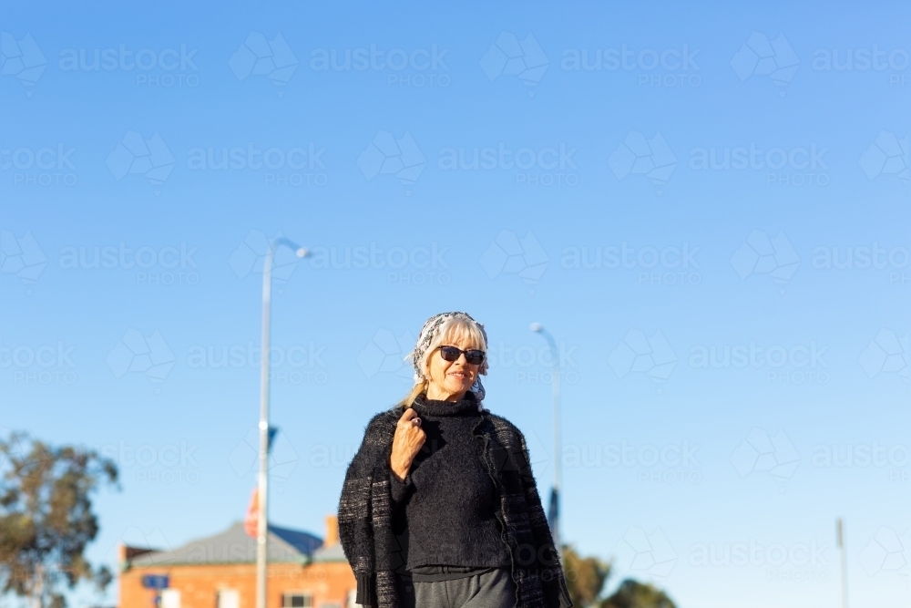 middle-aged woman wearing black against blue sky - Australian Stock Image