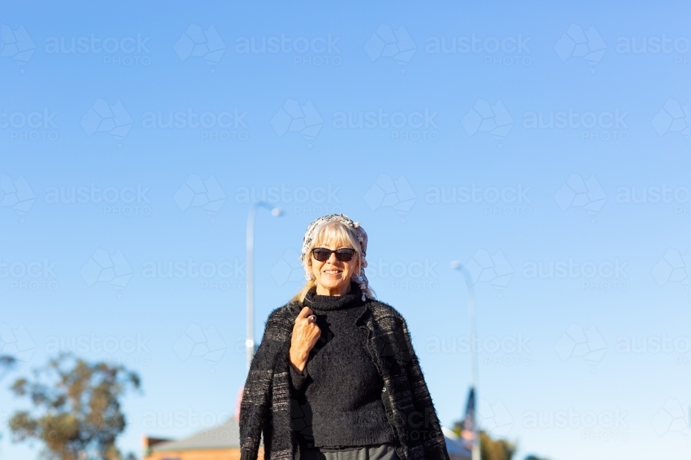 middle-aged woman wearing black against blue sky - Australian Stock Image