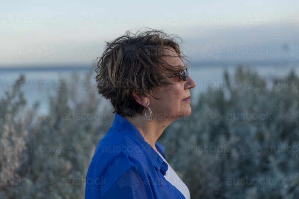 Middle eastern woman walking on shoreline at dusk - Australian Stock Image