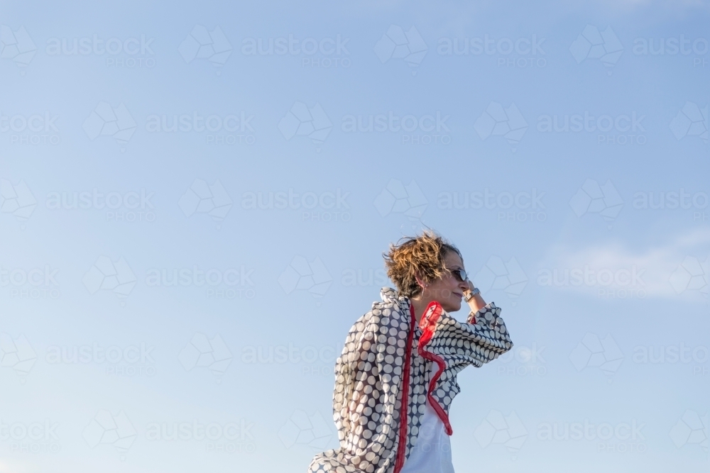 Middle eastern woman with fluttering scarf against blue sky - Australian Stock Image