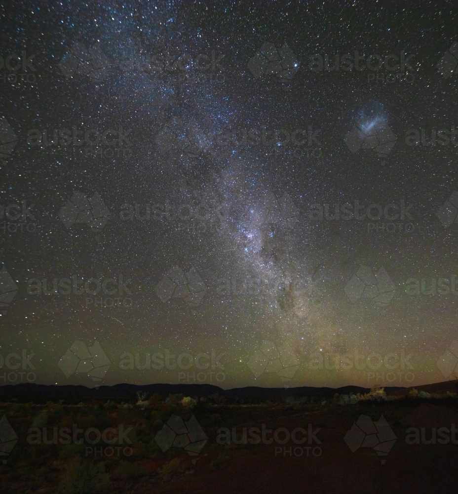 Miky Way and Magellanic Cloud over remote landscape - Australian Stock Image