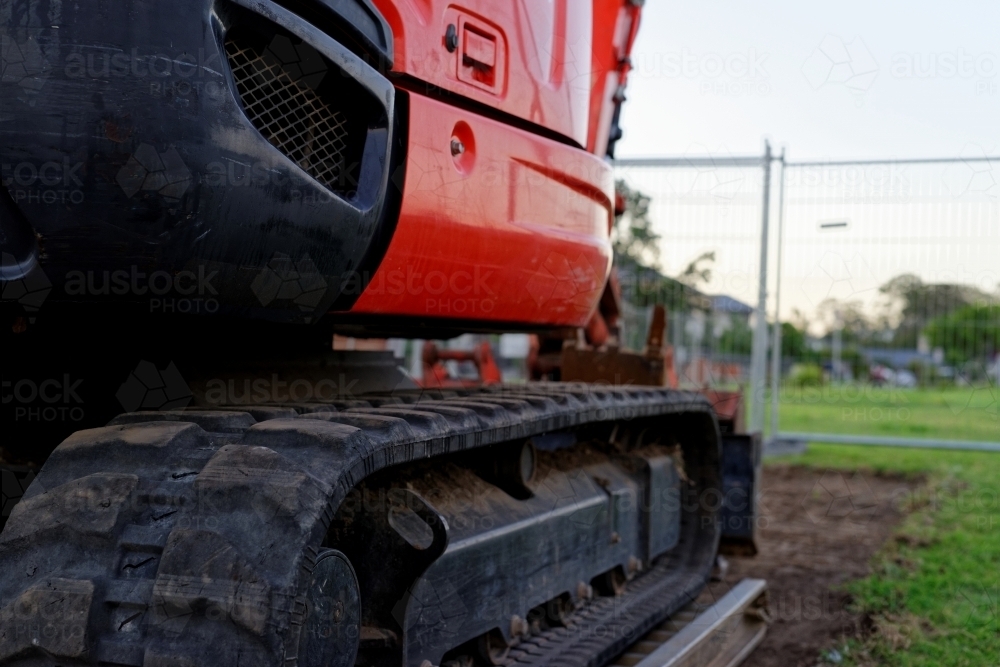 Mini digger standing idle at a construction site - red excavator - Australian Stock Image