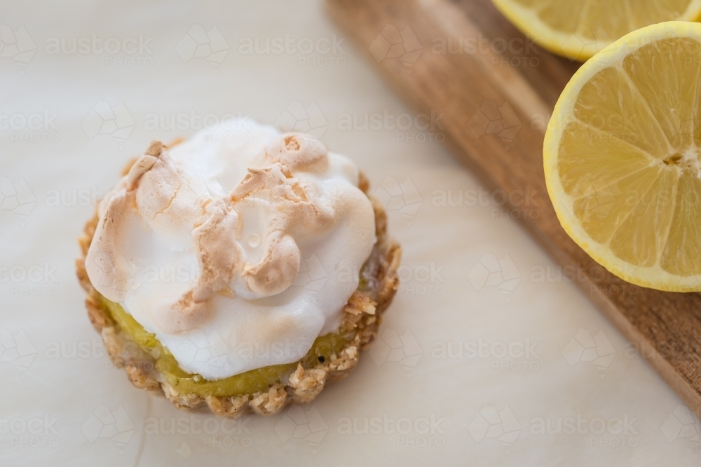 Mini Lemon Meringue Tarts with Lemons and board - Australian Stock Image