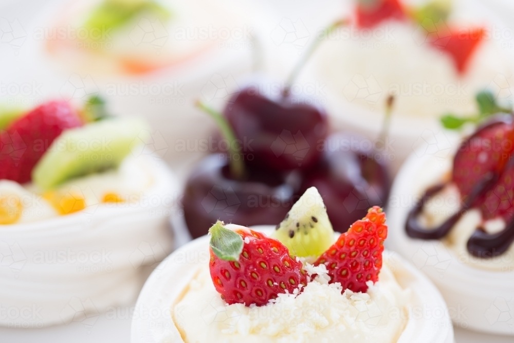 Mini Pavlova desserts topped with fruit on a white plate - Australian Stock Image