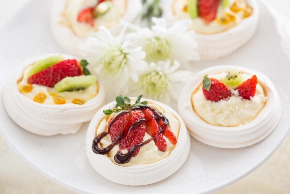 Mini Pavlova desserts topped with fruit on a white plate - Australian Stock Image