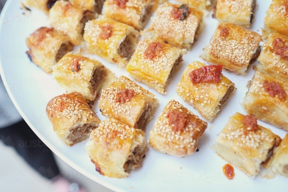 Mini sausage rolls on white serving plate - Australian Stock Image