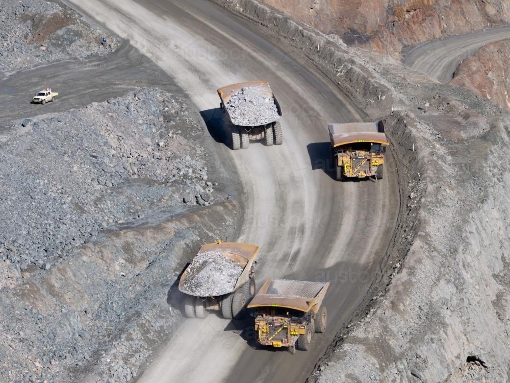Mining trucks moving along roadway of an open cut mine - Australian Stock Image