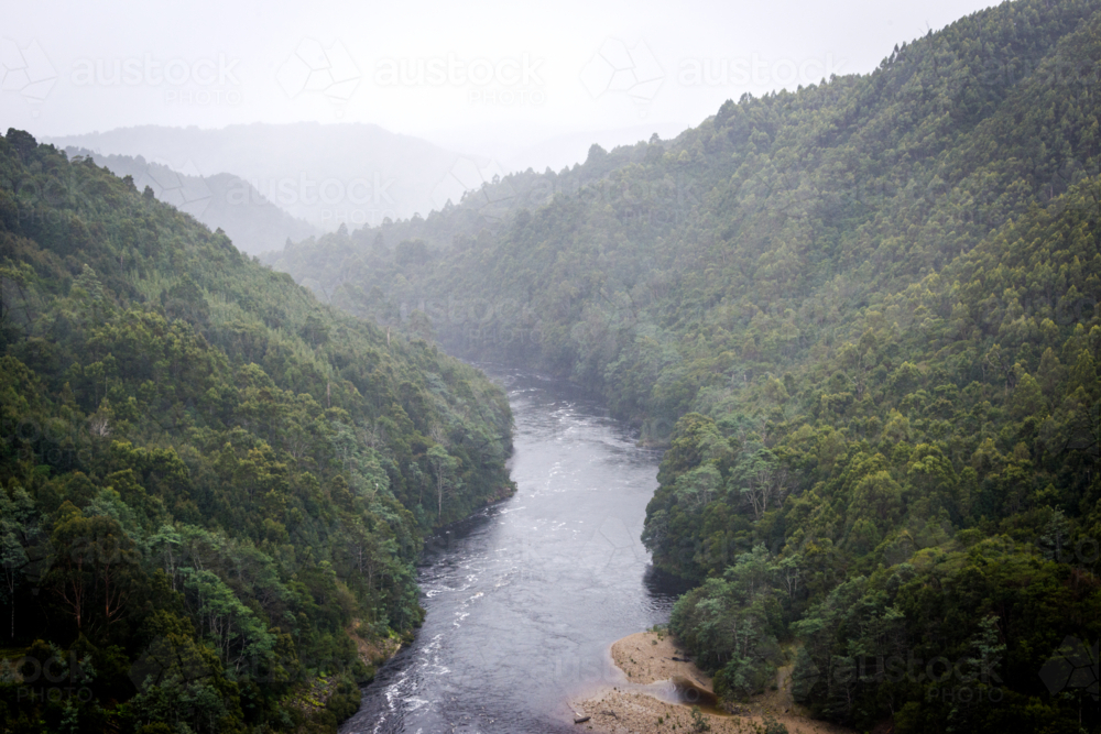 Misty view of the Pieman River winding through dense forest - Australian Stock Image