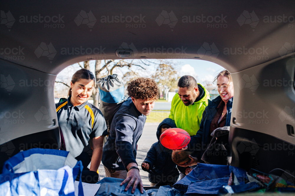 Mixed ethnicity family unpacking car boot - Australian Stock Image