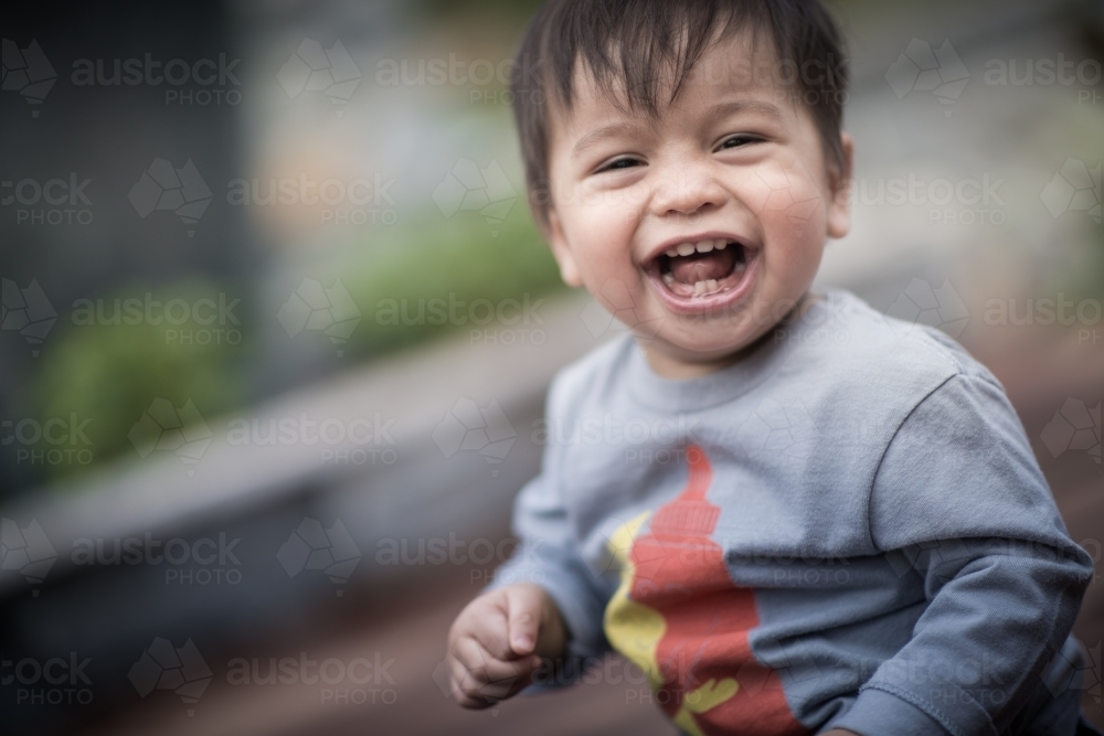 Mixed race 1 year old baby boy plays happily in his suburban backyard - Australian Stock Image