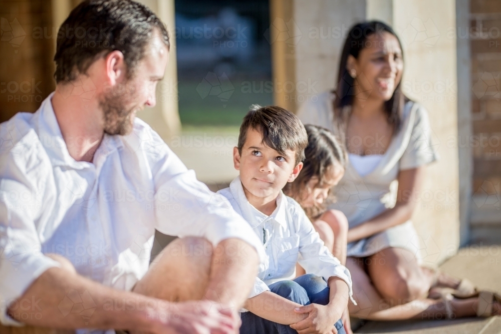 Image of Mixed race aboriginal and caucasian family sitting together son looking at father