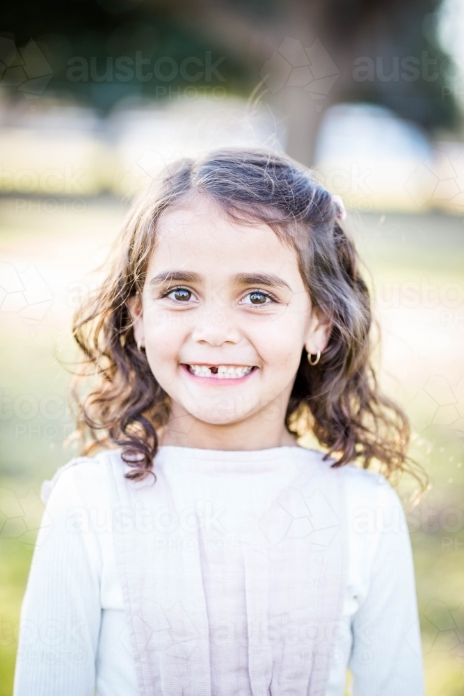 Mixed race aboriginal and caucasian girl with missing tooth smiling - Australian Stock Image