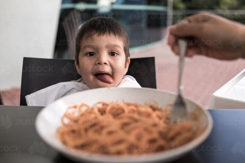 Mixed race boy eating pasta at a suburban Italian restaurant - Australian Stock Image