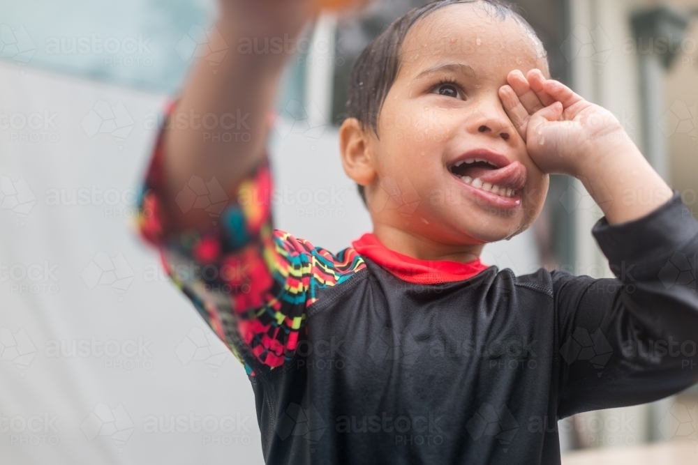 Mixed race boy playing in small backyard pool - Australian Stock Image