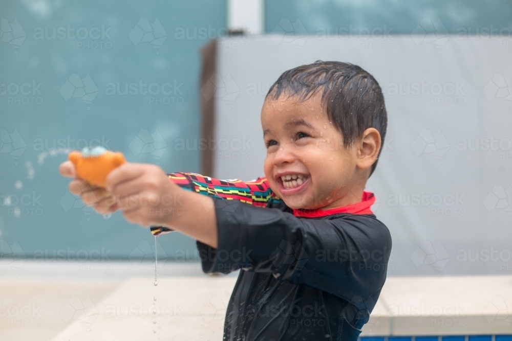 Mixed race boy playing in small backyard pool - Australian Stock Image