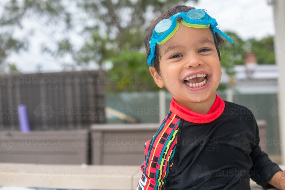 Mixed race boy playing in small backyard pool - Australian Stock Image