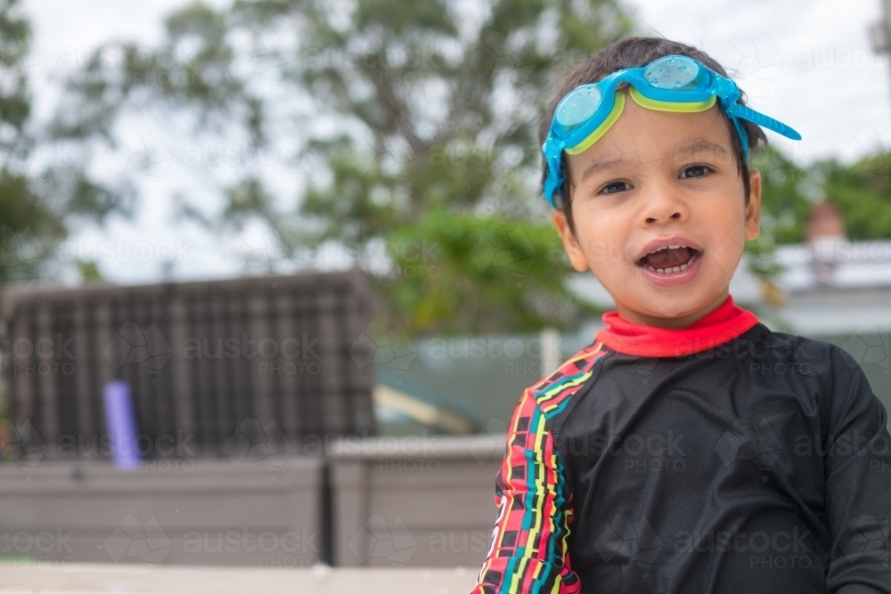 Mixed race boy playing in small backyard pool - Australian Stock Image