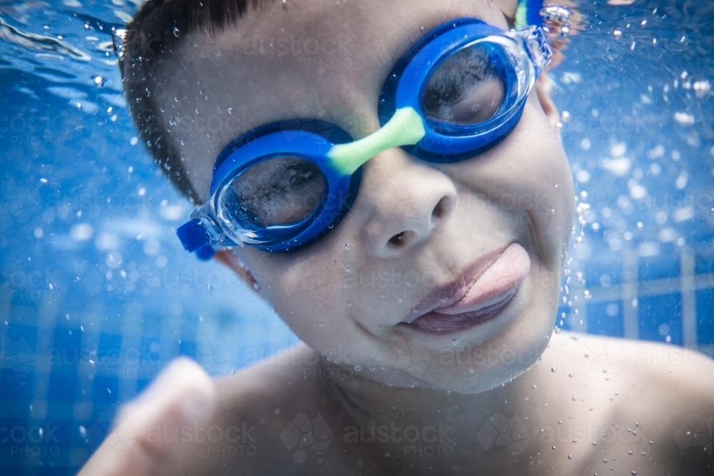 Mixed race boy swims and plays in a backyard pool - Australian Stock Image