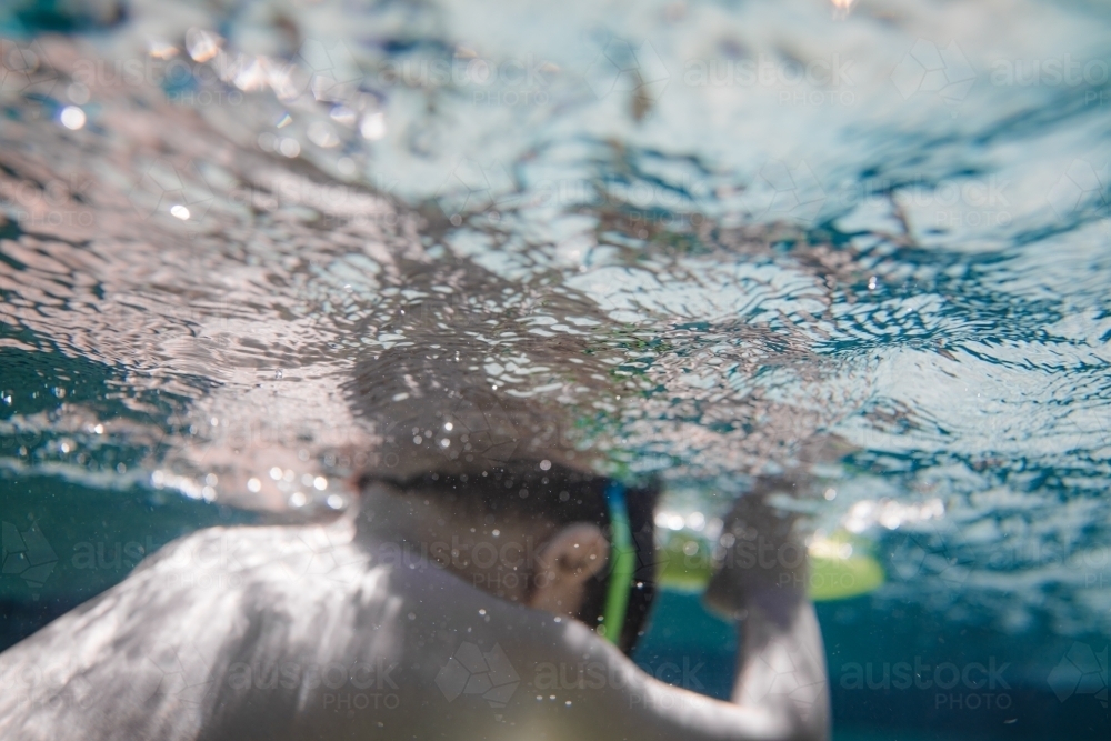 Mixed race boy swims and plays in a backyard pool - Australian Stock Image