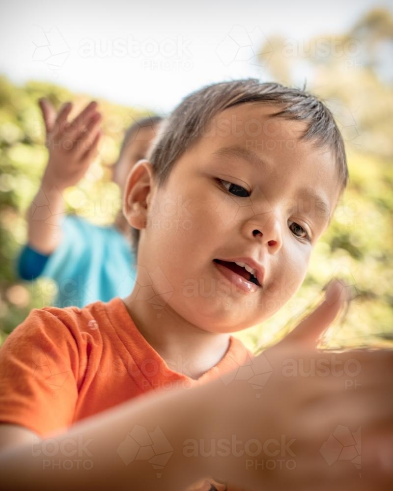 Mixed race boys play with bubbles in their suburban backyard - Australian Stock Image