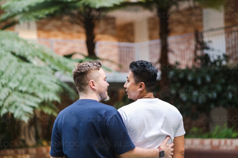 Mixed race gay couple hugging - Australian Stock Image