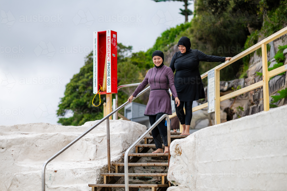 Mixed race women walking down the stairs towards the tidal pool - Australian Stock Image