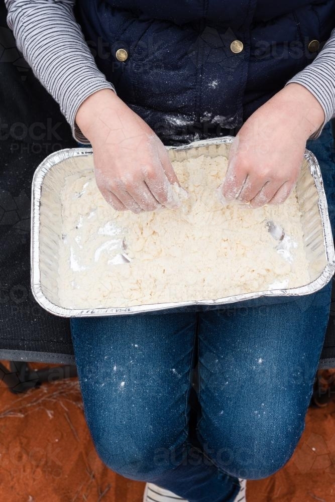 Mixing dough in a tray for making damper - Australian Stock Image