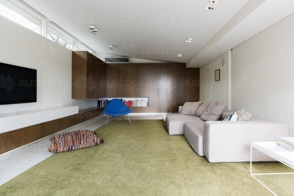 Modern living room with custom walnut cabinetry and large green wool rug - Australian Stock Image