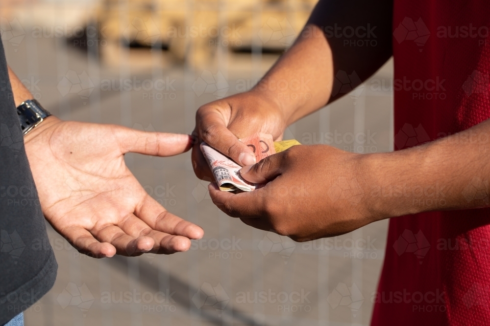 Image of money exchanging hands - Austockphoto