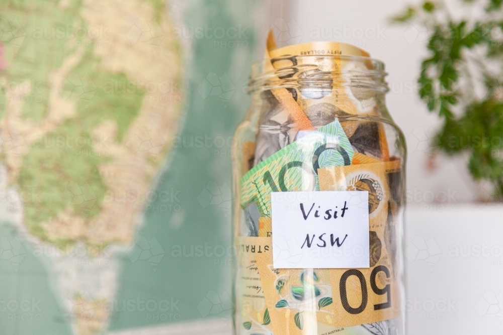 Money jar with visit NSW on it near map of Australia - travel concept - Australian Stock Image