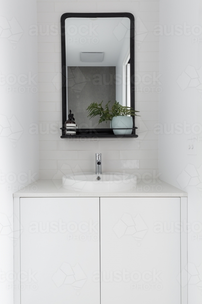 Monochrome powder room vanity black mirror and white tiling - Australian Stock Image