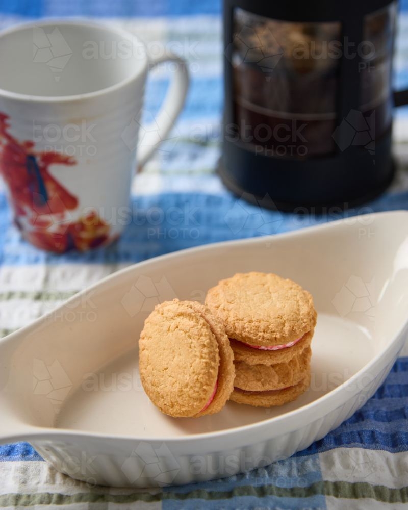 Monte Carlo biscuits on dish with cup and plunger behind. - Australian Stock Image