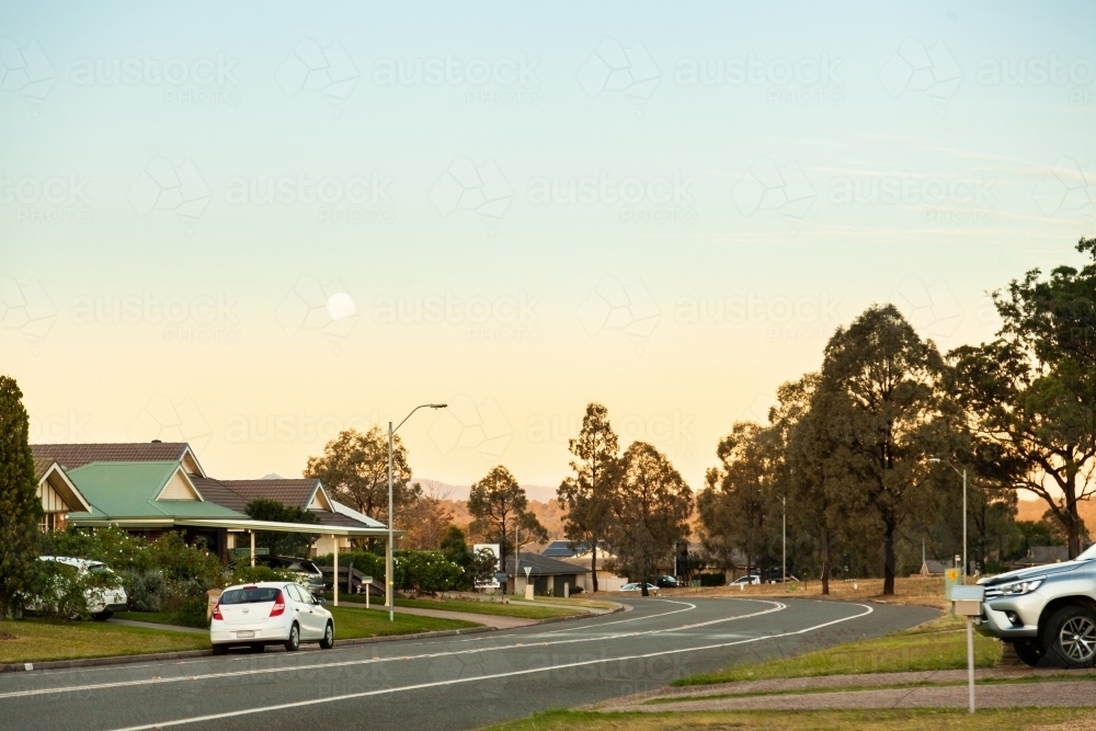 Moon in sky at dusk over suburban street in singleton - Australian Stock Image