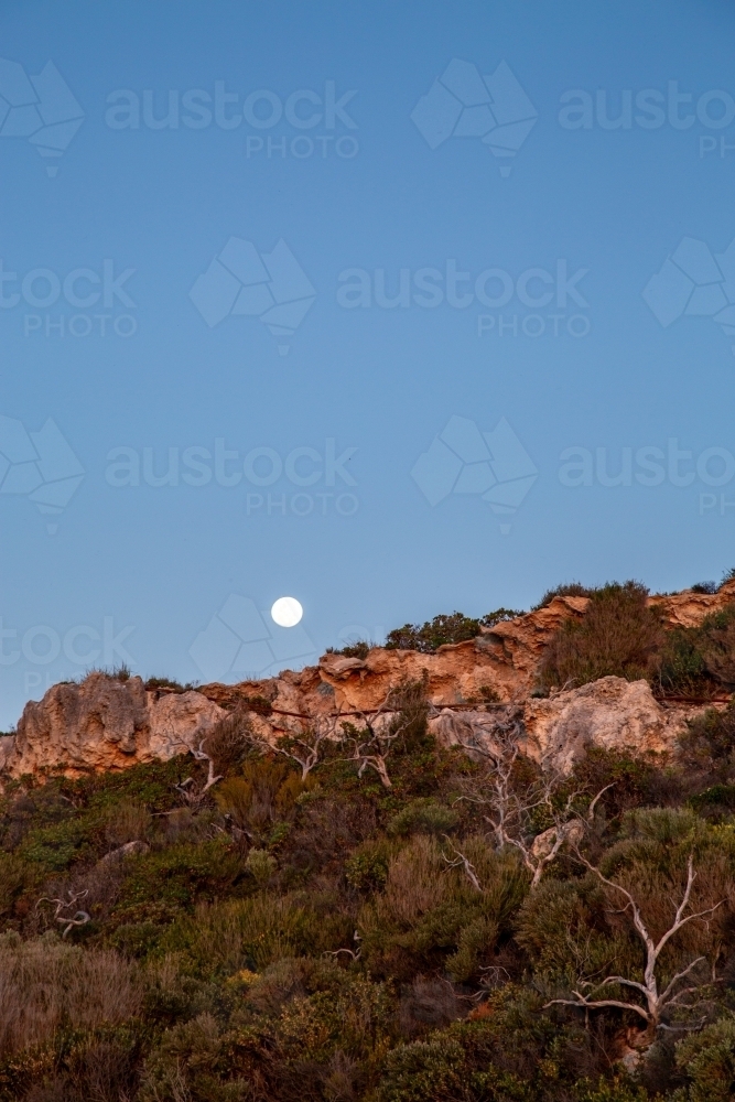 Moon rising above coastal cliff - Australian Stock Image