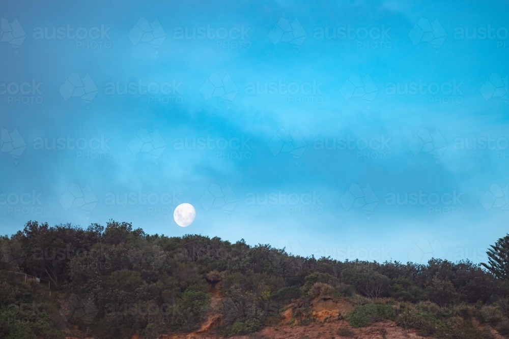 Moon rising over cliff at Redhead Beach, Newcastle NSW - Australian Stock Image