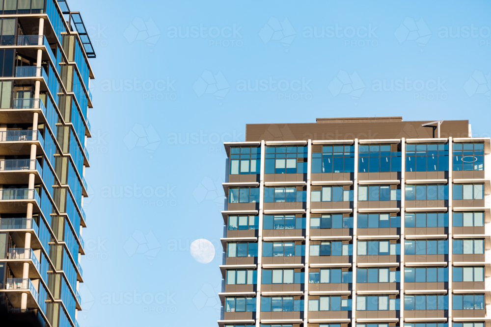 Moon visible in the daytime beside tall office building in Adelaide - Australian Stock Image