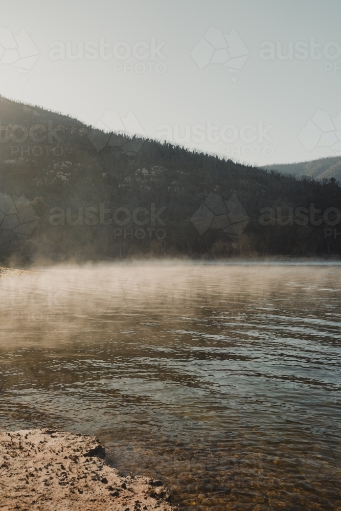 Morning fog lit up by the sun with mountains in the background - Australian Stock Image