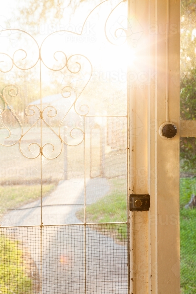 Morning sun flare through screen door of country homestead house - Australian Stock Image