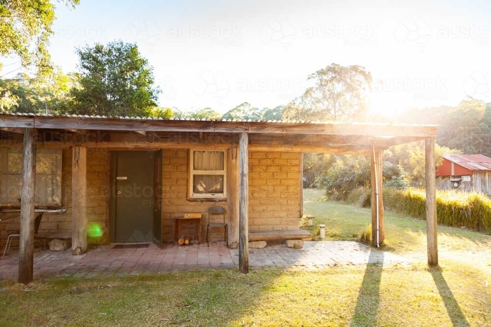 Morning sunlight flare over cottage in clearing - Australian Stock Image