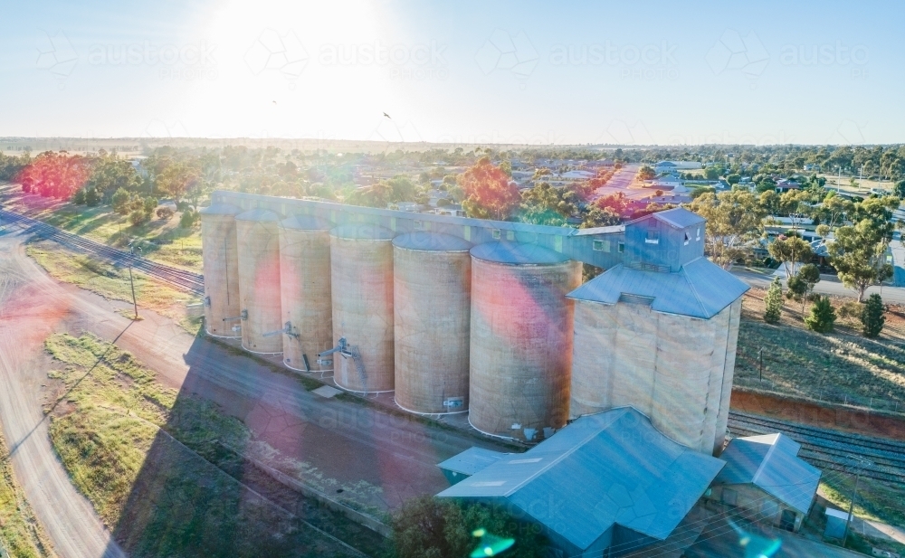Morning sunlight shining over wheat silo infrastructure beside a train line in the riverina - Australian Stock Image
